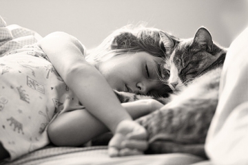 Kat en kind slapen samen hoofd aan hoofd